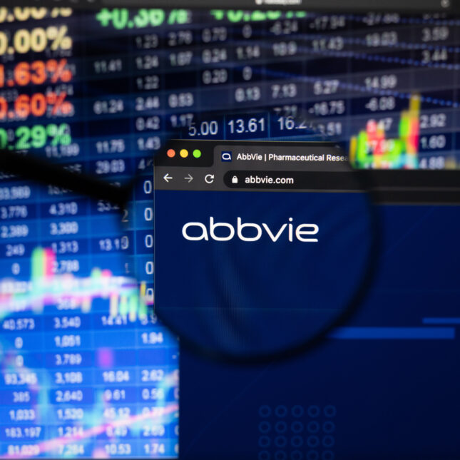 AbbVie company logo on a website with blurry stock market developments in the background, seen on a computer screen through a magnifying glass. -- coverage from STAT