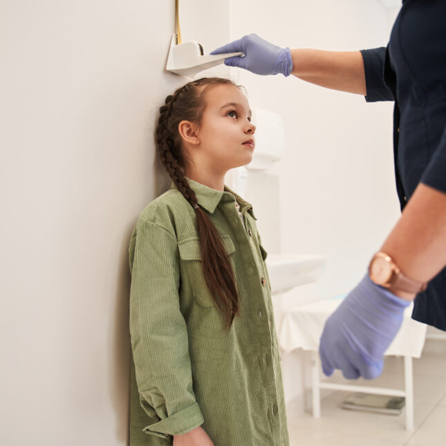 stock photograph of a child having their height measured at the doctors office for a story about BMI and obesity in children