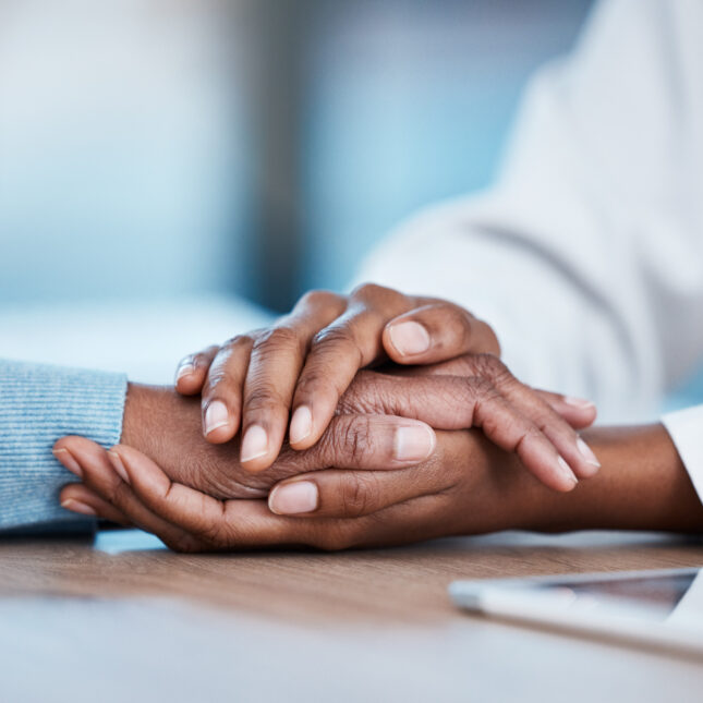 A Black doctor and patience embrace hands on a table. -- Health Equity coverage from STAT