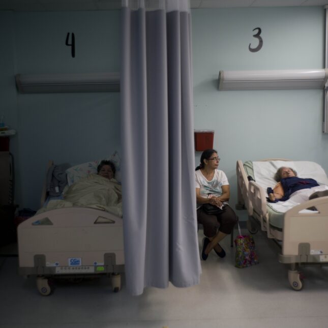 Two patients lay in their individual hospital beds divided by a curtain, with the left room being dark and the right room illuminated — first opinion coverage from STAT