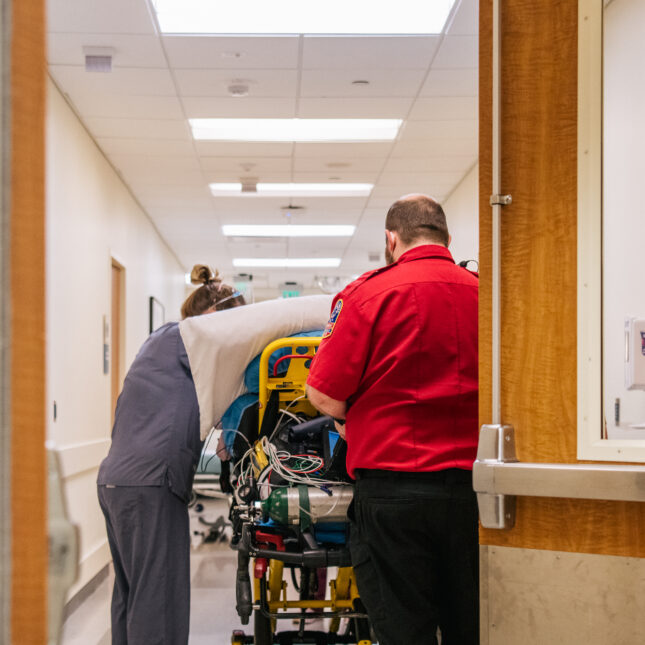 Emergency room nurses and EMTs tend to a patient in a hallway. -- First Opinion coverage from STAT