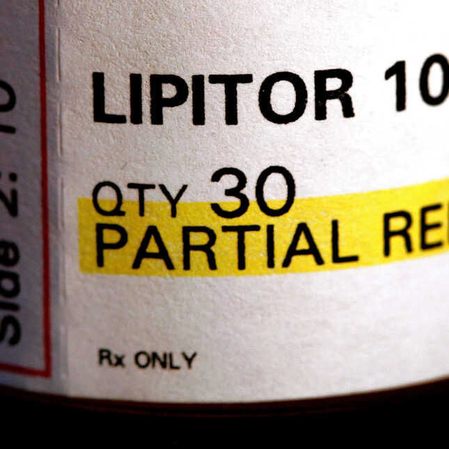 A close up photograph of the prescription label on a bottle of lipitor, a statin medication used to treat high cholesterol