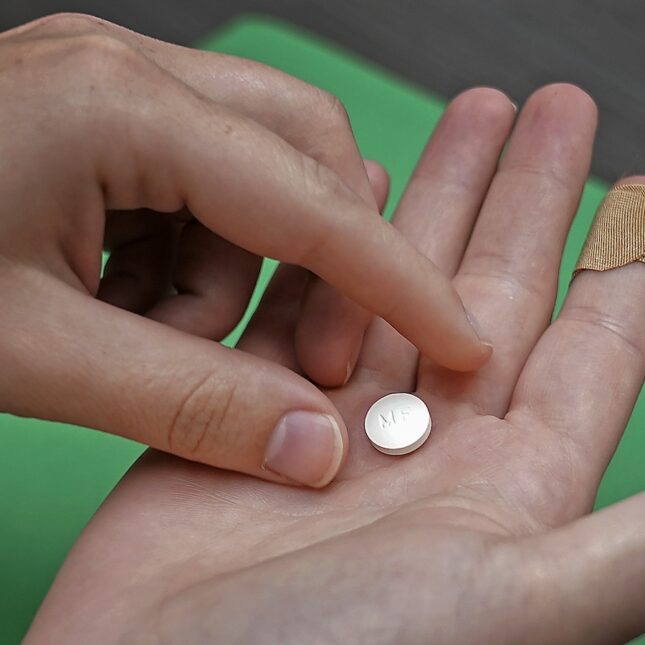 A mifepristone pill held in the hands of a patient.