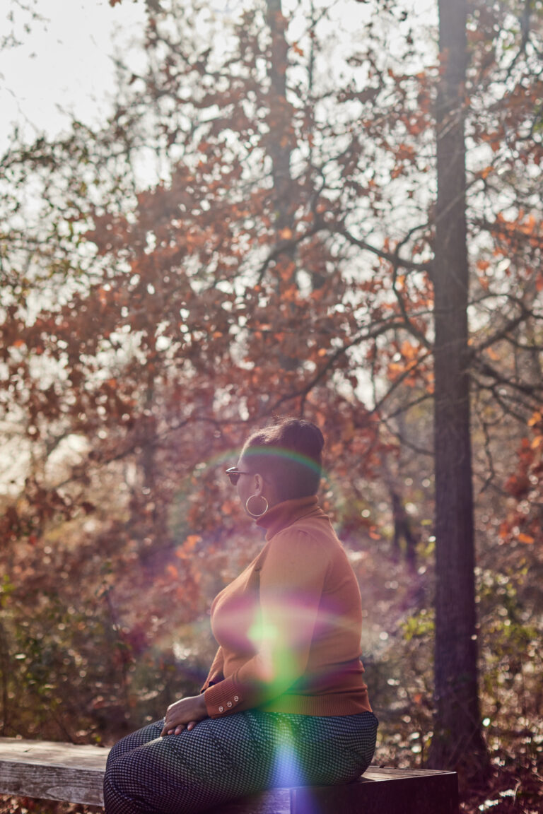 Photograph of an unidentified woman sitting on a bench in the forest 